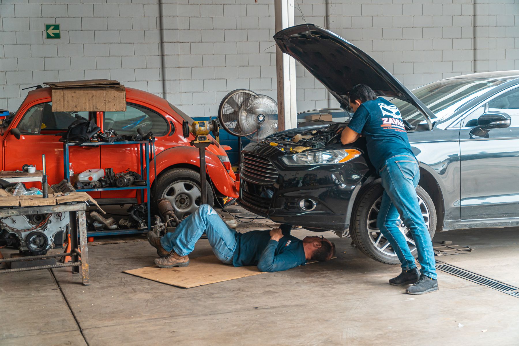 Automotive technicians repairing a vehicle in a commercial garage